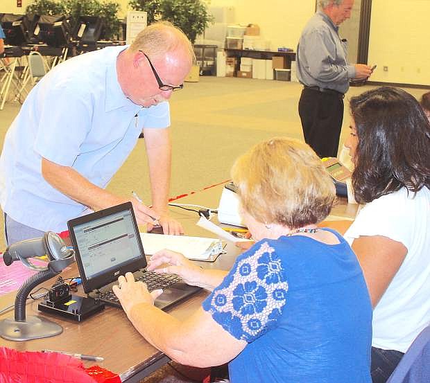 Nate Fiske votes early Tuesday morning as Peggy Ibbeson, left, and Wilma Mansfield use a new computer software program for checking in voters.