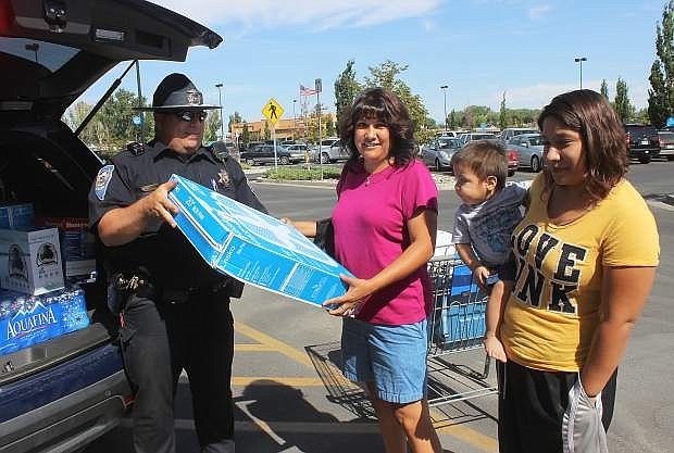 Juanita George hands a fan to Trooper Trent Barnes at Friday&#039;s Cram the Cruiser. With her are Danielle Roman and Denali Nez. The Nevada Highway Patrol collected fans, food, water and donations for senior citizens.