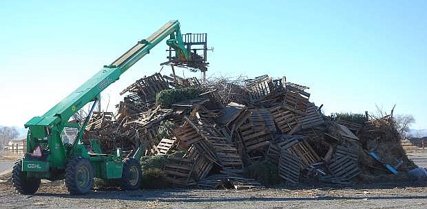 A county worker stacks wood on top of a pile for tonight&#039;sbonfire at the Churchill County Fairgrounds.