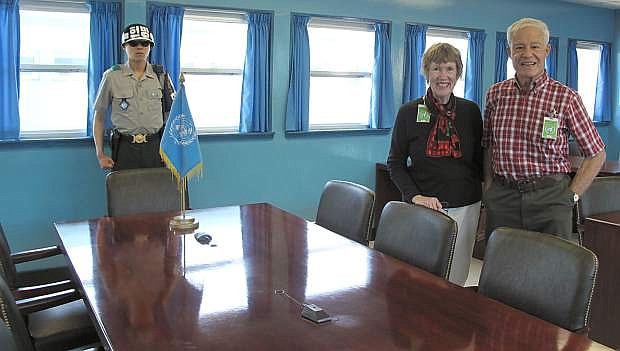 Ludie and David Henley are photographed on the North Korean side of the United Nations conference table, where truce talks have continuously been held since the Korean War ended in 1953. Guarding the South Korean side of the table in a South Korean soldier.