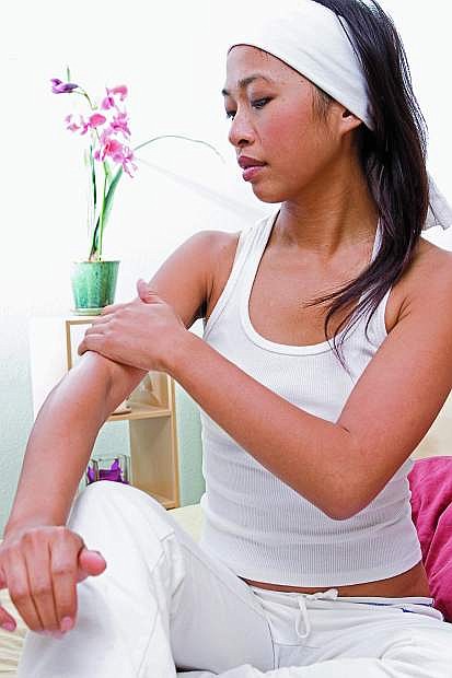 Young woman applying lotion to arm