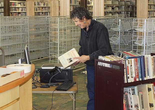 Volunteer Sue Geipel is using a new system to prepare books for checkout.