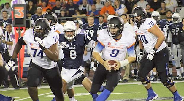 Boise quarterback Grant Hedrick (9) rolls to his left with help from Archie Lewis (74) and Steven Baggett (70). Coming toward Hedrick is the Wolf Pack&#039;s Ian Seau (8).