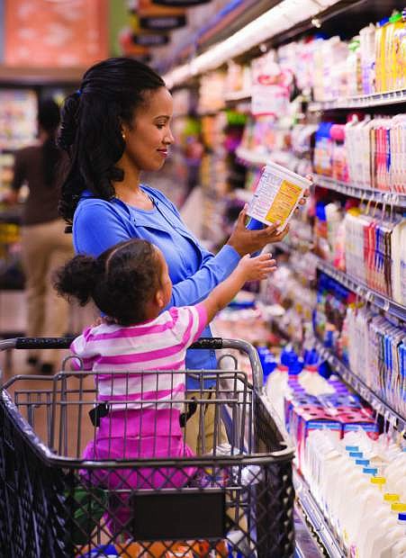 A woman shops withher  daughter in grocery store, checking labels.