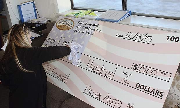 Jessilyn Strom writes out another donation check as part of Fallon Auto Mall&#039;s Pay It Forward campaign.