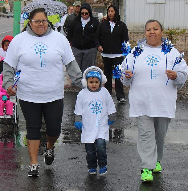 Carol Williams, right, wals with Vincent Fasthorse, center, and Tamika Fasthorse during Saturday&#039;s Pinwheels for Prevention walk. More photos on page 14.