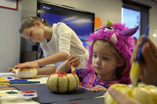 Abby Marschner, 10, left, and Annalise Schumacher,3,  create some Halloween art at the Carson City Library Monday. As part of the library&#039;s Halloween festivities, dozens of children decorated pumpkins or gourds and took part in a costume contest.