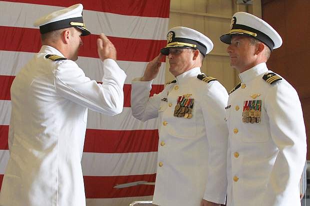 Cmdr. Brian Ferguson, center, outgoing commanding officer of VFC-13,  salutes Capt. Nichols, left, commander Tactical Support Wing, while the incoming CO, Cmdr. Wayne Oetinger looks on.