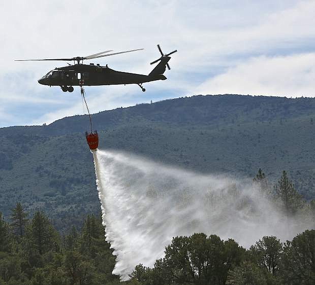 An Army National Guard Blackhawk drops a 660 gallon load of water on a wooded area during fire training Wednesday near Markleeville.