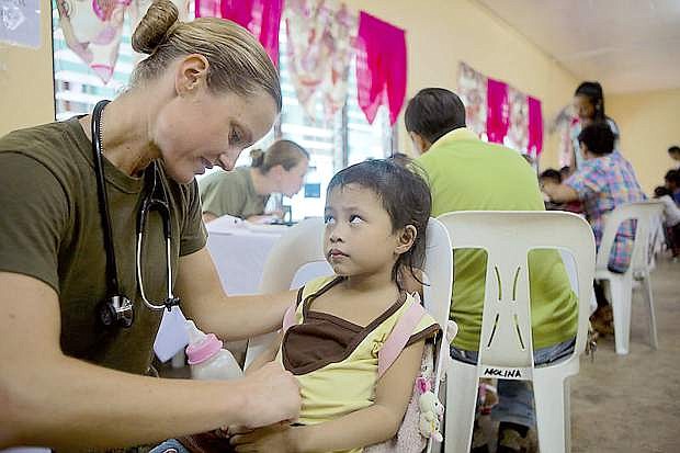 U.S. Navy Lt. Stephanie Ellis Brashear, family practitioner, 3d Medical Battalion, 3d Marine Expeditionary Brigade, III Marine Expeditionary Force, treats a Filipino child during a cooperative health engagement at Bigaa Elementary School, Legazpi City, Albay, Republic of the Philippines, Sept. 26, 2013 as part of Amphibious Landing Exercise 2014 (PHIBLEX 14).