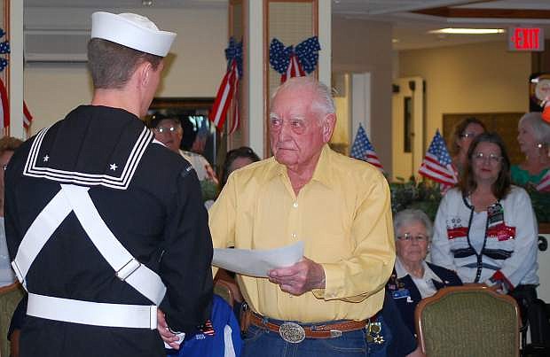 Navy airman Nick Lysne of the Navail Air Station Fallon color guard presents a certificate of appreciation to veteran Roland Christiansen as onlookers watch. Highland Village conducted a veterans recognition program on Monday.