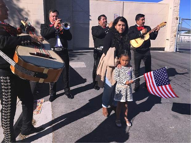 Jacqueline Lima, 20, walks with her four-year-old sister, Karla, holding an American flag, and gets serenaded by a mariachi group after Lima voted for the first time, Tuesday, Nov. 8, 2016, in Las Vegas. Immigrant advocates in Las Vegas worked to get more U.S.-born Latinos to the polls on Election Day as early voter numbers suggest a surge in Hispanic voters. Lima voted for Democrat Hillary Clinton. (AP Photo/Russell Contreras)