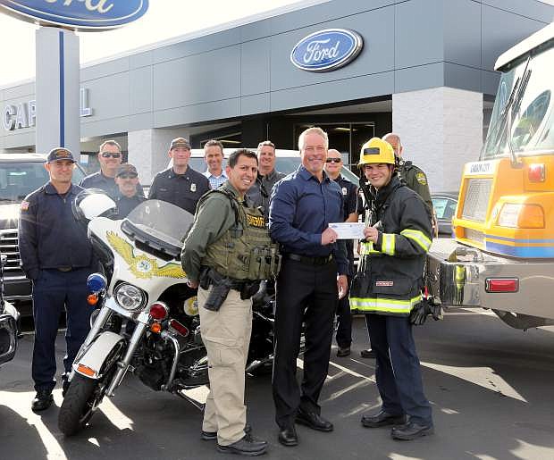 Tim Milligan, general manager of Capital Ford presents a $2,500 check on Tuesday to Carson City firefighter Dustin Peterson and Carson City Sheriff&#039;s Sgt. Daniel Gonzales to benefit the Holiday with a Hero program.