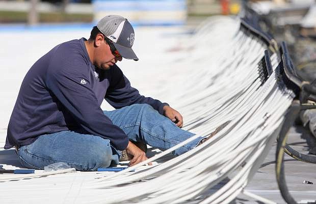 Lane Pickel, with the Carson City Recreation Department works on installing cooling tubes for the public ice rink on Tuesday afternoon.