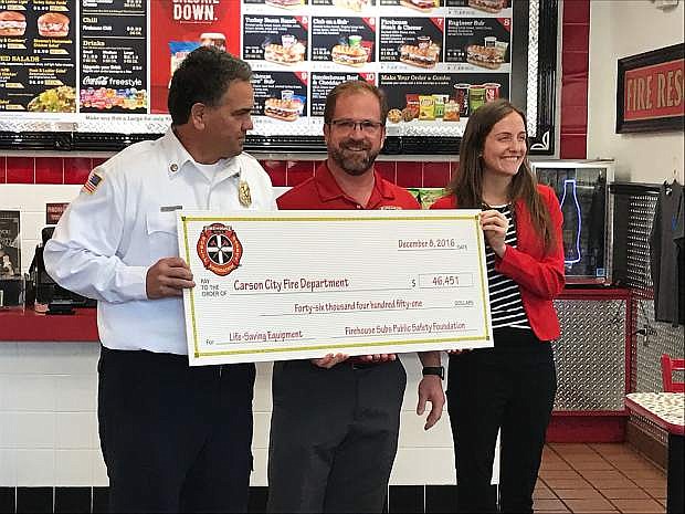Carson City Fire Chief Bob Schreihans accepts a check from Firehouse Subs co-owner Damon Kreizenbeck and Public Safety Foundation Senior Manager of Foundation Programs Jackie Gubbins.