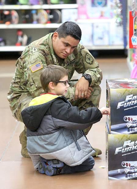 Army Guard Sgt. Robert Diaz helps 6-year-old Luis pick out a toy at the annual Holiday with a Hero program on Wednesday at Walmart.