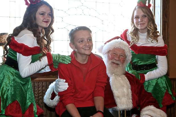 13-year-old Holden Egelston takes a photo with Santa and his elves Michelle Hawkins (left) and Shylin Roberts (right) Saturday at Adele&#039;s.