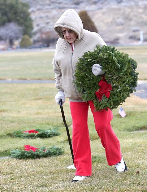 Betty Johnson, 93, carries an armful of Christmas wreaths to decorate the grave markers of veterans on Wednesday at Lone Mountain Cemetery.