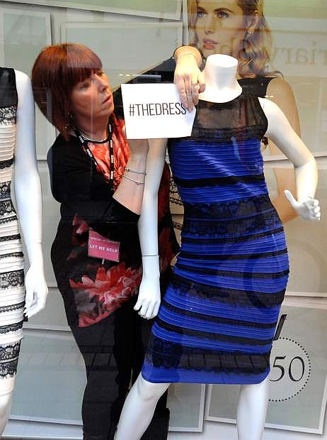 Shop manager Debbie Armstrong adjusts a two tone dress in a window display of a shop in Lichfield, England, Friday Feb. .27, 2015. It&#039;s the dress that&#039;s beating the Internet black and blue. Or should that be gold and white? Friends and co-workers worldwide are debating the true hues of a royal blue dress with black lace that, to many an eye, transforms in one photograph into gold and white  (AP Photo/Rui Vieira)