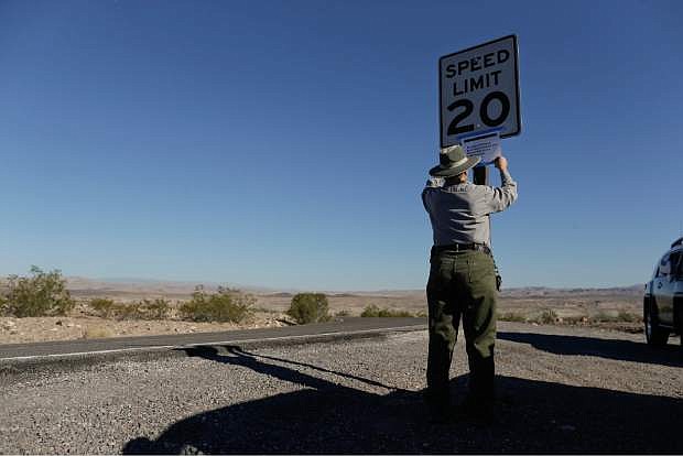 Lake Mead National Recreation Area park maintenance worker Donna Curry tapes up a sign notifying visitors that the picnic facility is closed, Tuesday, Oct. 1, 2013, near Boulder City, Nev. A partial government shutdown, caused by a budget impasse in Congress, has forced the closure of public sites including the nation&#039;s national parks.  (AP Photo/Julie Jacobson)