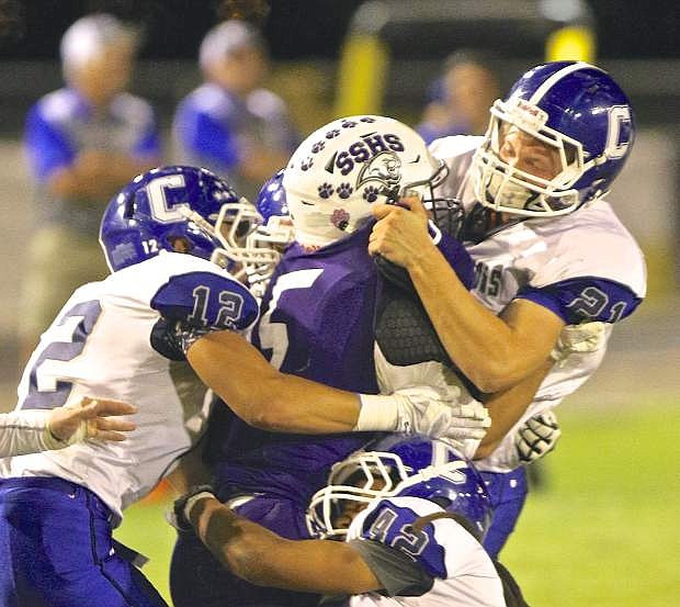 Carson linebacker Jace Keema (21) gets some help bringing down Spanish Springs running back Travis Vargas (5) from his teammates last Friday night in Sparks.