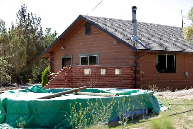 A partially burned home sits behind police tape Tuesday, Aug. 6, 2013, near the U.S.-Mexico border in Boulevard, Calif. The husband of a woman whose body was found in the house said Tuesday that he knew the man suspected of killing his wife and abducting one or both of their children. (AP Photo/Gregory Bull)