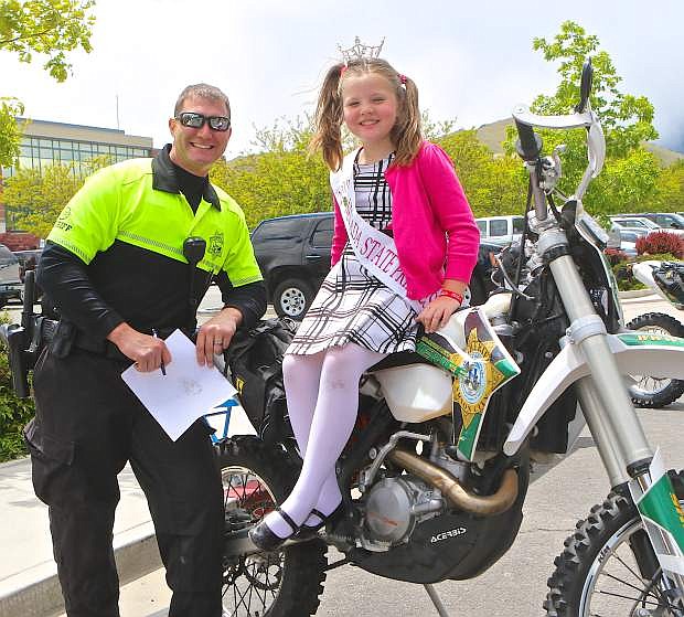 Nevada State Princess to Miss Lake Tahoe Talia Clinkendere, 8, poses for a photo with Motor Unit Deputy Joey Trotter Saturday at the Sheriff&#039;s station.