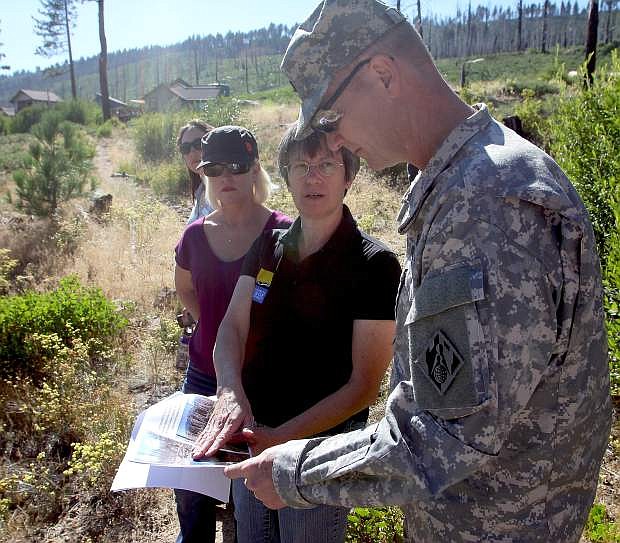 Penny Stewart, of the California Tahoe Conservancy, shows Col. Michael Farrell, of the U.S. Army Corps of Engineers, photos of an area effected by the Angora Fire. Farrell stood at the site during a tour around Lake Tahoe on Monday.