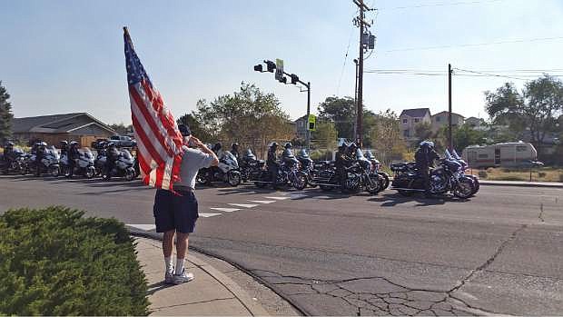 A man salutes motorcycle officers as they leave a Carson City mortuary to escort the body of Carson City Deputy Carl Howell to his funeral on Aug. 20, 2015 in Carson City, Nev. Howell was killed in the line of duty on Aug. 15.  (AP Photo/ Michelle Rindels)