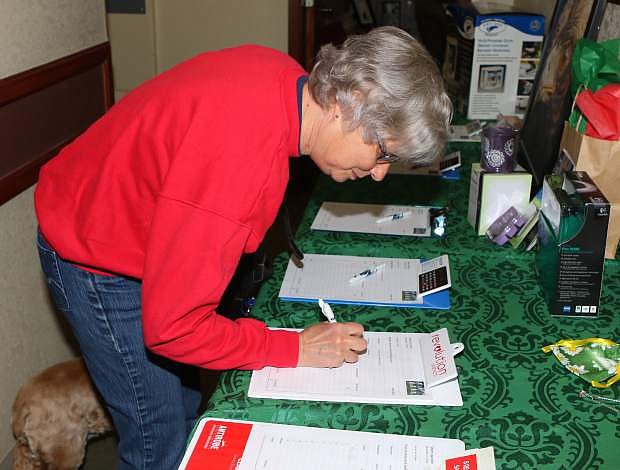 Kathy Graff puts in a silent auction bid at Sierra Veterinary Hospital&#039;s fundraiser on Saturday.