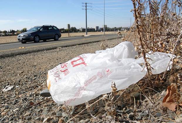 FILE-In this file photo taken Friday, Oct. 25, 2013, a plastic shopping bag liters the roadside in Sacramento, Calif. Gov. Jerry Brown has signed legislation on Tuesday, Sept. 30, 2014 imposing the nation&#039;s first statewide ban on single-use plastic bags.  (AP Photo/Rich Pedroncelli)