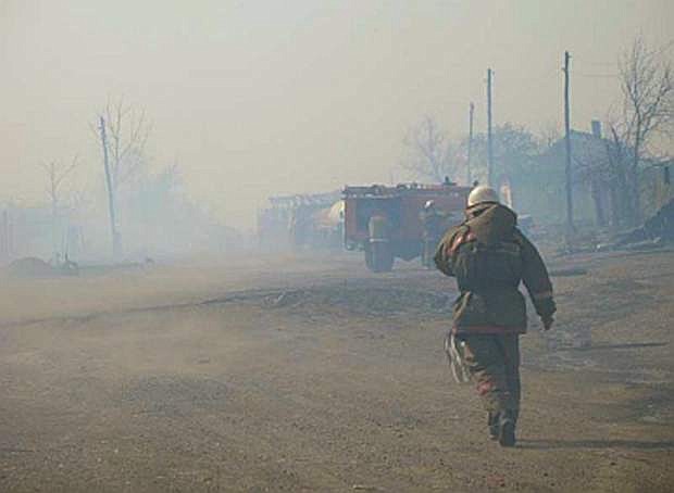 In this undated photo taken from the Website of the Ministry for Emergency Situations, Khakassia branch Monday, April 13, 2015, a firefighter walks through smoke from the fire in Khakassia, a region in southeastern Siberia, Russia. Russian authorities say out-of-control agricultural fires have killed at least 15 people, injured hundreds more and destroyed or damaged more than 1,000 homes in Siberia. The fires were started by farmers burning the grass in their fields, but spread quickly because of strong winds. (Ministry for Emergency Situations, Khakassia branch in Siberia via AP)