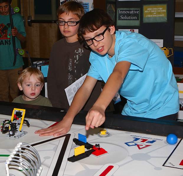 Dean Poppenga III explains Lego robotics to 12-year-old Nevan McIwee and his 4-year old brother Julian during the STEM/STEAM Night at Eagle Valley Middle School.