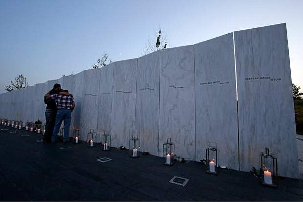 Visitors embrace in front of the wall containing the 40 names of the crew and passengers of Flight 93 at the Flight 93 National Memorial during a candlelight remembrance on Tuesday, Sept. 10, 2013. (AP Photo/Gene J. Puskar)
