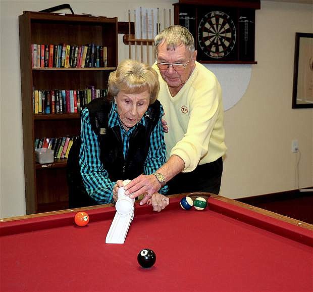Nils Sharpe, 85, right, teaches Pearl Garrett, 93, a game of pool with his ramp invention which replaces a cue stick.