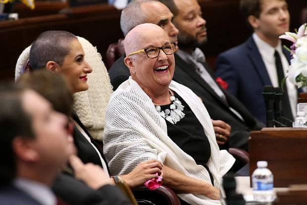 Nevada Sen. Debbie Smith, D-Sparks, center, is recognized on the Senate floor at the Legislative Building in Carson City, Nev., on Wednesday, April 8, 2015. Smith returned to work Wednesday, two months after having a malignant brain tumor removed. Her daughter Erin Marlon, on her right, and husband Greg, on her left, both shaved their heads with her. (AP Photo/Cathleen Allison)