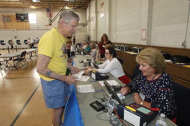 Carson City resident Jim Sadilek signs in to vote with intake clerk Ruthann Wagner on Tuesday.