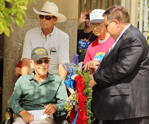 World War II veterans Ivan Bell Woodward (in wheelchair) and Ray Gawronski (red shirt) assist Fernley Mayor Roy Edgington, right, with the posting of the wreath.