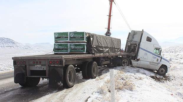 A tractor-flatbed slid into two Nevada Highway Patrol vehicles Friday morning south of Fallon on US 95, totaling one and damaging the other.