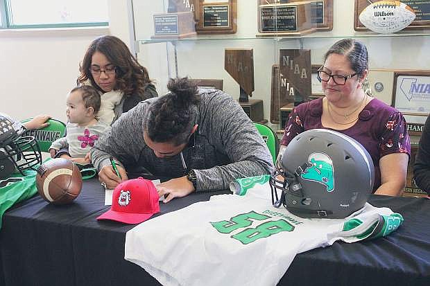 T.J. Mauga, center, is joined by his mother and sister as he signs a letter of intent to join Fresno State&#039;s football team this fall.