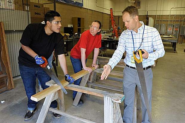 Western Nevada College instructor Nigel Harrison, right, provides a lesson in using a saw to Susanne Whimple and Cristian Avila during a construction class in Carson City.