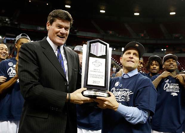 Mountain West Conference Commissioner Craig Thompson, left, presents Nevada coach Eric Musselman with the trophy after Nevada defeated Colorado State 79-71 in an NCAA college basketball game for the conference title, Saturday, March 11, 2017, in Las Vegas. (AP Photo/Isaac Brekken)