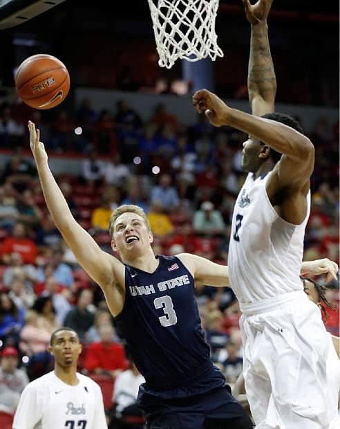 Utah State&#039;s Sam Merrill shoots as Nevada&#039;s Leland King Jr. defends during the second half in the Mountain West Conference tournament Thursday in Las Vegas.