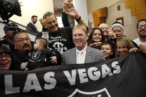 FILE - In this April 28, 2016, file photo, Oakland Raiders owner Mark Davis, center, meets with Raiders fans after speaking at a meeting of the Southern Nevada Tourism Infrastructure Committee in Las Vegas. America&#039;s most popular sport is in the midst of its greatest migration in a quarter century. In a little over a year, three NFL franchises have either moved, announced a resettlement or filed paperwork seeking to relocate. (AP Photo/John Locher, File)
