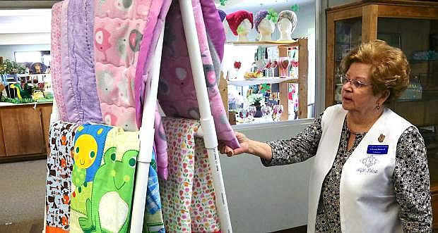 Volunteer LaVonne Birdwell arranges quilts on a stand located near the Senior Center gift shop that is open to the public.