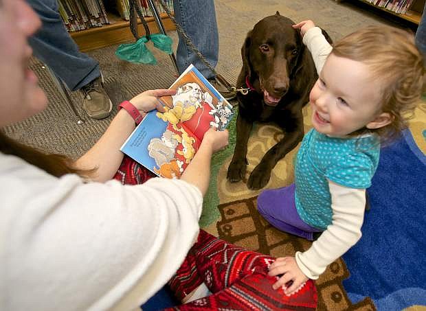 Shaughnessy Fernandez, 2, reads (with the help of her mom Roxanne) to chocolate lab &#039;Moose&#039; Saturday at the Carson City Library.