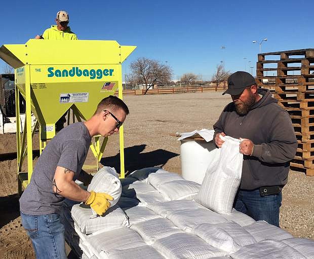 DeAl Dankers, top, along with Dee Allsop, right, and James Clippard, a volunteer from Naval Air Station Fallon, fill sandbags Thursday morning at the fairgrounds.