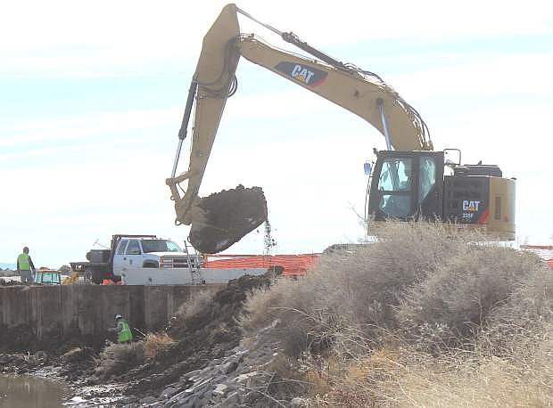 A CAT excavator removes dirt from the embankment before the sheet piling is cut at the weir contruction site.