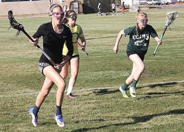 Sadie O&#039;Flaherty, left, Jaidyn Delgado and Aubrey Renfroe, right, carry balls as they race across the field.