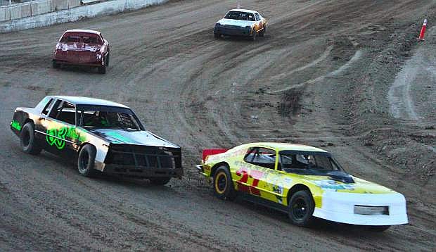 Racecars bank around the first turn in Rattlesnake Raceway&#039;s track during the season opener.